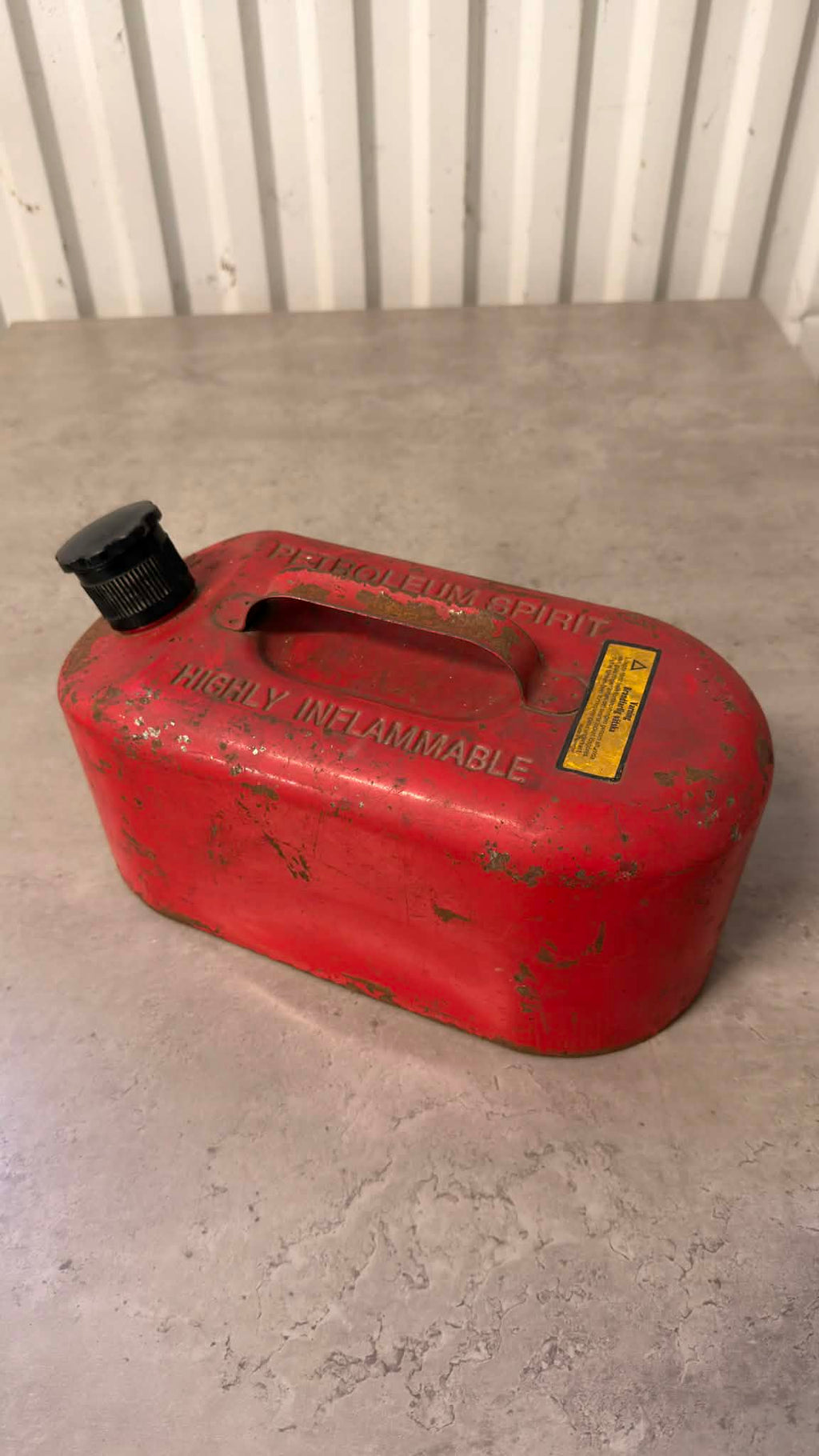 En svart bensindunk från DRH Customs med anpassad design, av plast och med handtag för enkel hantering.