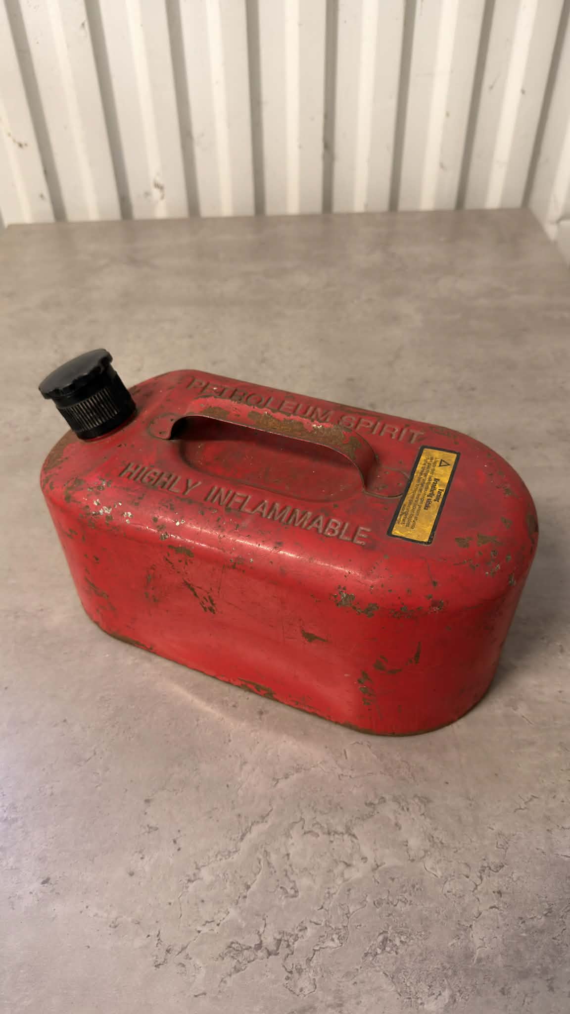 En svart bensindunk från DRH Customs med anpassad design, av plast och med handtag för enkel hantering.
